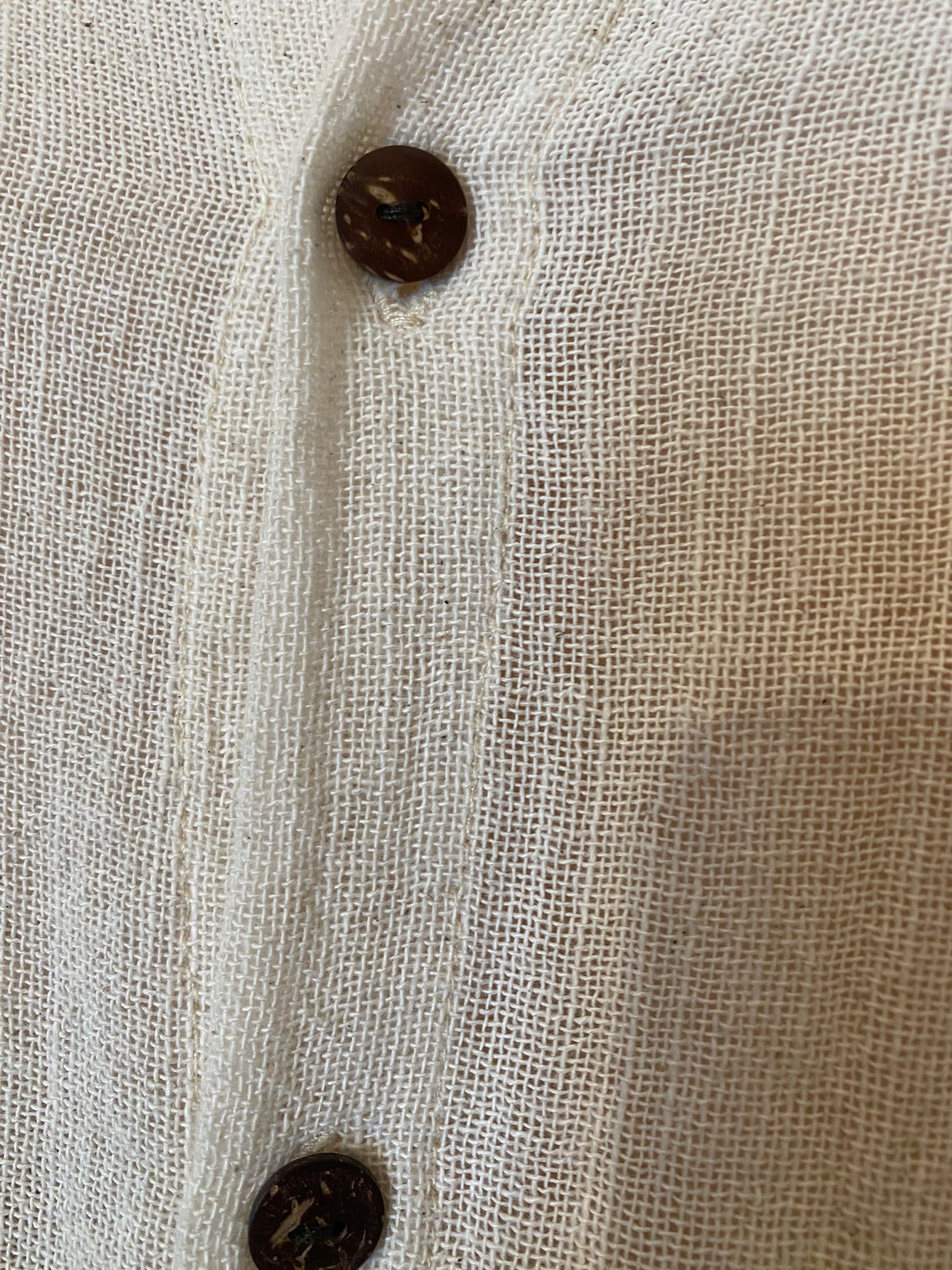 Close-up of ramie fabric natural fibre texture with button detail on women’s long shirt